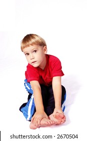 A Cute Four Year Old Boy Wearing Red And Blue Who Is Sitting And Touching His Toes.