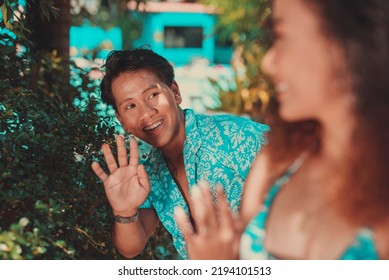 A Cute And Friendly Asian Man Saying Hi To An Attractive Woman. Wearing Light Blue Summer Luau Hawaiian Outfit.