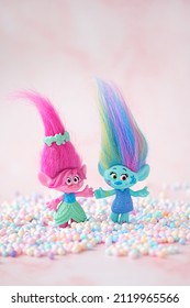 Cute friends trolls with colorful balls confetti on blurred pink background close up. Harper Pinsel and Queen Poppy - modern toy hasbro trolls. concept of children's games, fun, toys, friendship