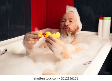 Cute funny bearded man playing with rubber ducks in bubble bath relaxing at home. - Powered by Shutterstock