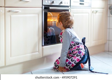 Cute funny blond kid boy baking muffins in domestic kitchen. Child having fun with helping, sitting near ofen and waiting for cupcakes. - Shutterstock ID 495907291