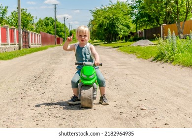 Cute funny blonde little young toddler kid boy learning riding bicycle,child motorcycle on road.Children physical development,childhood daycare,kindergarten concept,rural countryside nature landscape.