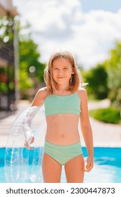 Cute and funny blonde teenage girl in a swimsuit with an inflatable lifebuoy near the pool. Safe rest with children by the water. travel and tourism.