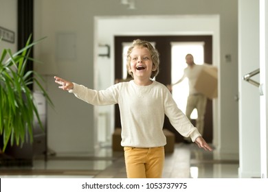 Cute Funny Boy Running In Hallway Exploring Big Luxury House Relocating With Parents, Excited Child Son Jumping Playing Entering New Modern Home, Happy Kid Enjoying Moving Day With Family Concept