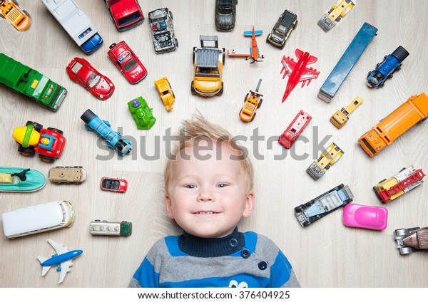 Cute funny Boy with\
toy cars around him