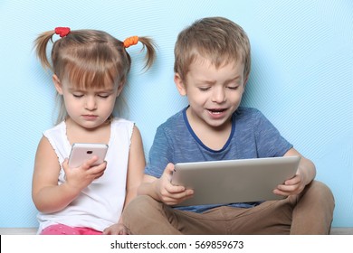 Cute Funny Children With Tablet Computer And Mobile Phone On Color Background