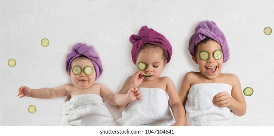 Cute, Funny Kids In White Towels And Terry Cloth Bath Turbans With Cucumber Face Treatments