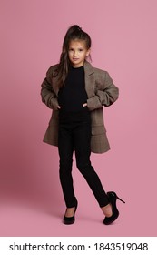 Cute Funny Little Child Girl In White Oversized Mother's Jacket And Shoes On Pink Background. Child Playing Adult Life