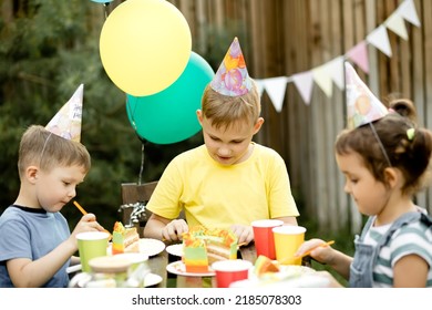 Cute Funny Nine Year Old Boy Celebrating His Birthday With Family Or Friends And Eating Homemade Baked Cake In A Backyard. Birthday Party For Kids