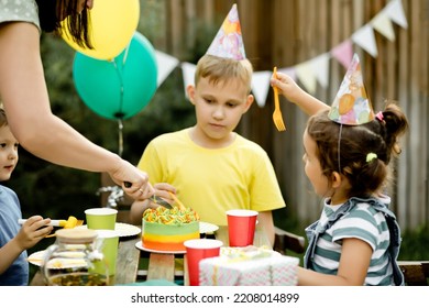 Cute Funny Nine Year Old Boy Celebrating His Birthday With Family Or Friends And Eating Homemade Baked Cake In A Backyard. Birthday Party For Kids