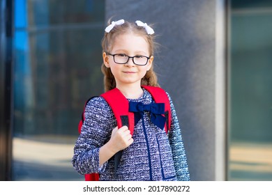 cute funny smart schoolgirl with schoolbag. back to school. happy beautiful child, clever girl with glasses and poor eyesight go to first grade.