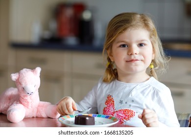 Cute Funny Toddler Girl Eating Chocolate Ice Cream At Home. Happy Healthy Baby Child Feeding Plush Lama Toy With Sweet Ice-cream. Lovely Kid Enjoying Dessert Pudding.