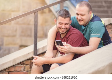 Cute Gay Couple Chatting About Online Content On Their Phone