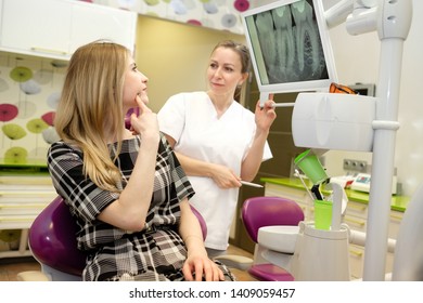 Cute Girl 25 Years Old On Review Of Woman Dentist, Sitting In Chair. Dentist Female Explaining X-Ray To Older Man. Dental Care For Older People. Dentistry, Medicine And Health Care Concept