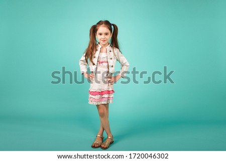 Cute girl 5 year old wearing in dress posing in studio. Girl full-length portrait on blue studio background. Happy fashion baby girl with expressive emotions.