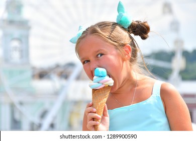 Cute Girl In A Beautiful Dress Eating Marshmellow Outdoors.Ferris Wheel In The Background. Portrait. Close Up