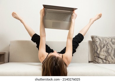 cute girl in black clothes uses laptop in freaky unusual position - Shutterstock ID 2140276025