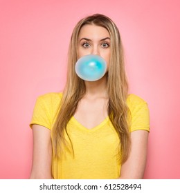 Cute Girl Blowing Blue Bubble Gum Near Pink Wall 