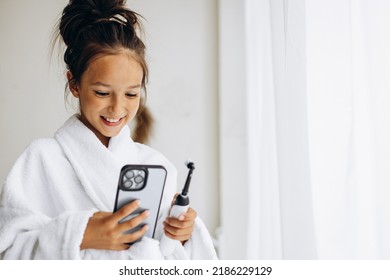 Cute Girl Brushing Teeth And Using Phone