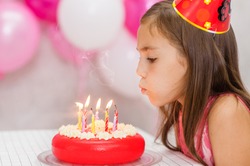 Cute Girl Celebrating Her Birthday And Blowing Candles On Cake.