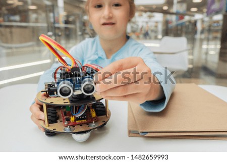 A cute girl constructs metal robot and program it. The boards and microcontrollers are on the table. STEM education inscription. Programming. Mathematics. The science. Technologie. DIY. 