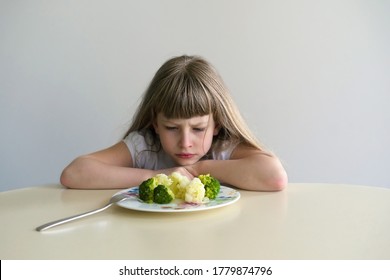 Cute girl doesn't want to eat broccoli and cauliflower