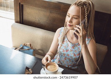 Cute girl with dreadlocks drinks coffee. - Powered by Shutterstock