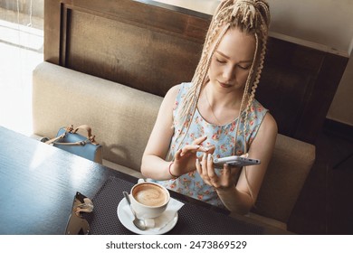 Cute girl with dreadlocks drinks coffee. - Powered by Shutterstock