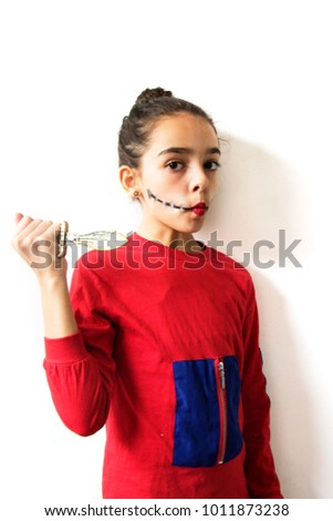Cute girl dressed as a rag doll. Cloth doll make-up for Halloween. Portrait of girl in red dress with small knife over white background.