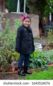 A Cute Girl Dressed For The Rainy Season, Stading In A Backyard With California Native Plants.