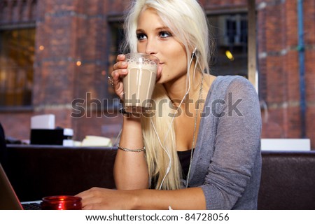 Cute girl drinking coffee on a cafe in the city.