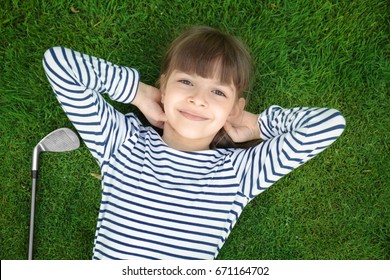 Cute girl with driver lying on golf course