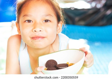 Cute Girl Eating Sweets, Sloppy Mouth On A Rubber Raft Floating On The Pool.On A Blurry Background.