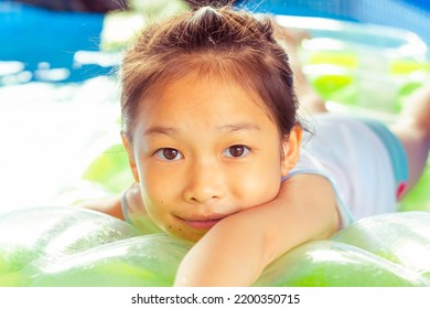 Cute Girl Eating Sweets, Sloppy Mouth On A Rubber Raft Floating On The Pool.On A Blurry Background.