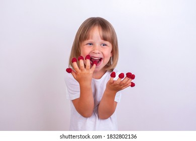 Cute girl eats raspberries from her fingers.