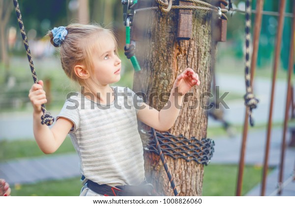 Cute girl enjoying activity in a climbing\
adventure park. Girl goes on hinged\
trail.