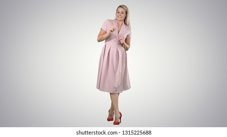 Cute girl full length in pink dress talking to camera   smiling gradient background 