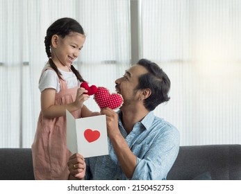 Cute girl and handsome Asian father putting red hearts together while reading card. Father's day or birthday. - Shutterstock ID 2150452753