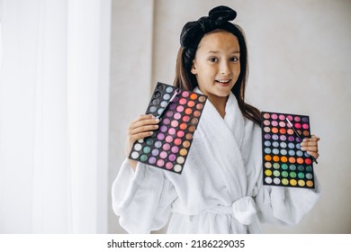 Cute girl holding eye shadows palette preparing to do makeup