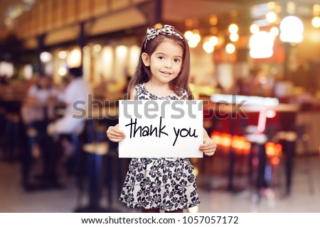 cute girl holding a piece of paper with the words Thank You , blur restaurant background 