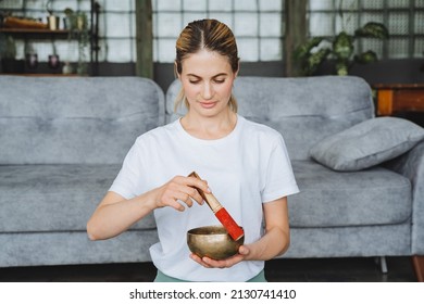 A cute girl holds a Tibetan singing bowl in her hands. Therapeutic sound of high frequencies and vibrations from bowls. Meditating girl. High quality photo