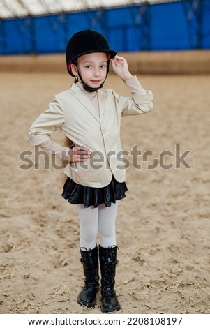 Cute girl in jockey cap. Prepairing for horse riding.