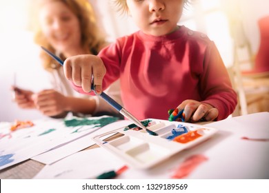 Cute Girl In Kinder Garden Painting Eggs For Easter With Mom. They Are Having Fun While Working On Eggs