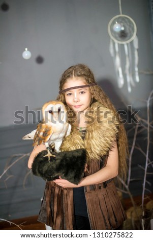 Cute girl with long hair with a white owl in her arms in the style of boho 