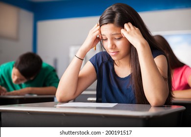 Cute girl looking worried while taking a test in a classroom
