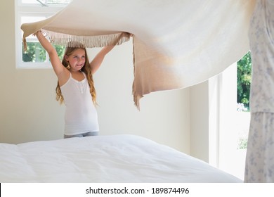 Cute Girl Making Bed With Mother In House