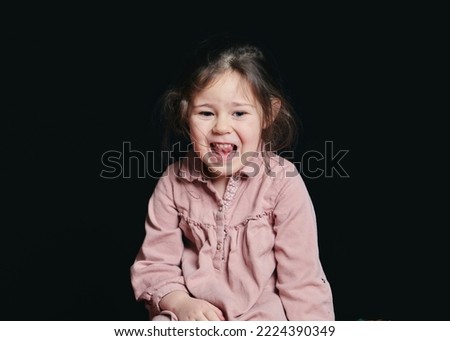 cute girl making expressive faces in the studio against a black background