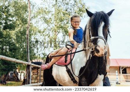 Cute girl on a red horse outdoor. Hippotherapy for young children with down syndrome, therapy after many serious diseases.