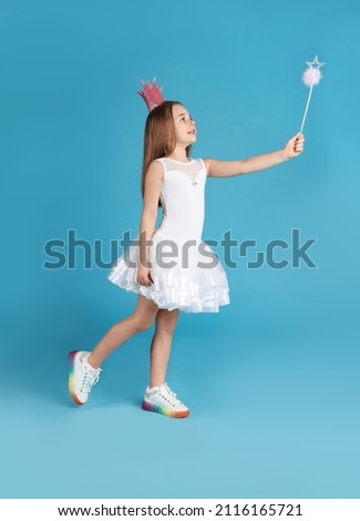 Cute girl in pink crown with magic wand on light blue background. Little princess
