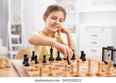 Cute girl playing chess at table in room - Powered by Shutterstock